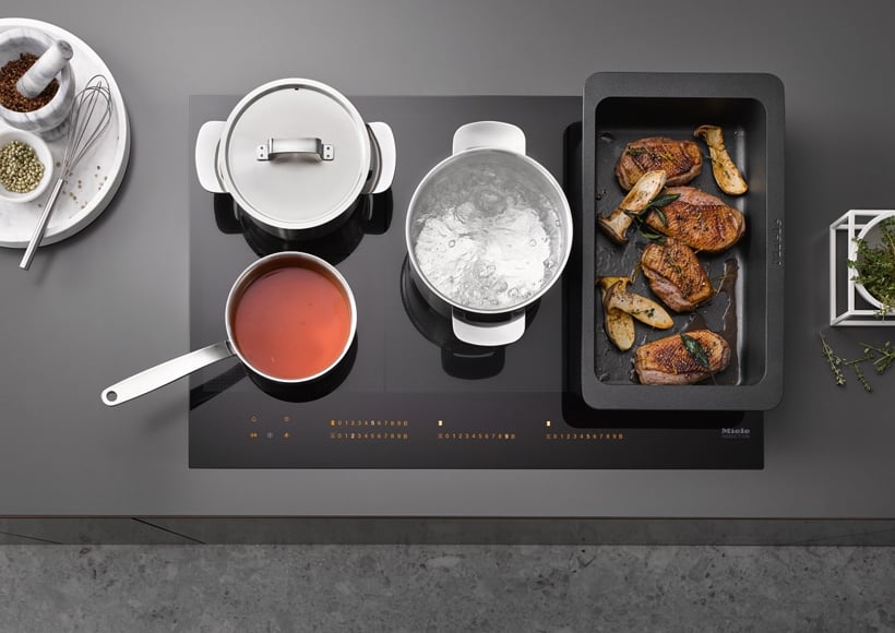 Miele Induktionskochfeld auf dem mit verschiedenen Töpfen gekocht wird