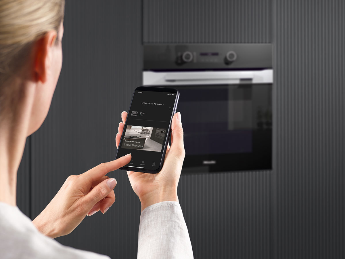 Frau bedient einen Miele Backofen per Handy-App
